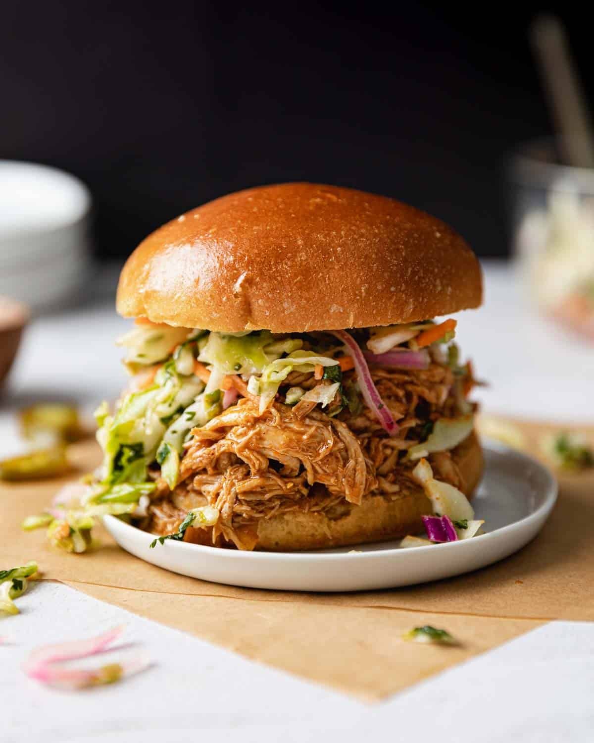 Side profile image of instant pot bbq chicken sandwich on white plate.