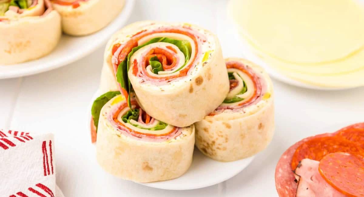 Up close image of Italian pinwheels with cheese and meats on the side.