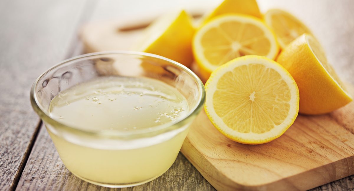 Up close image of lemon juice with lemons in the background.