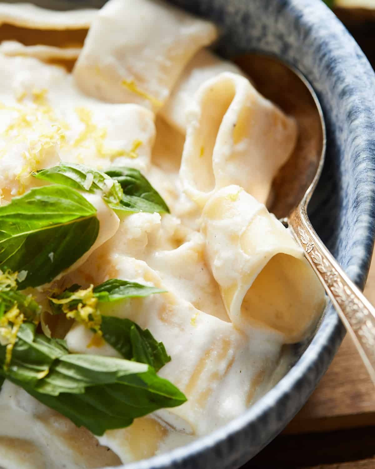 Close up shot of lemon ricotta pasta with lemon zest, basil, and parmesan on top.
