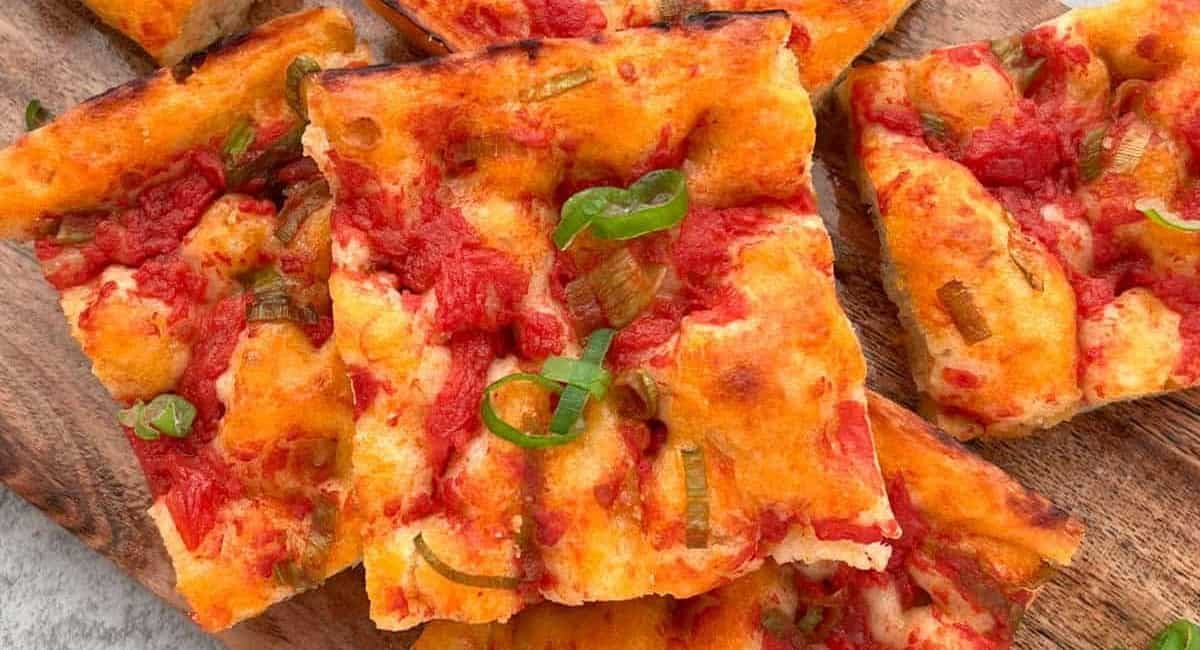 Overhead up close image of ligurian focaccia on wooden board.