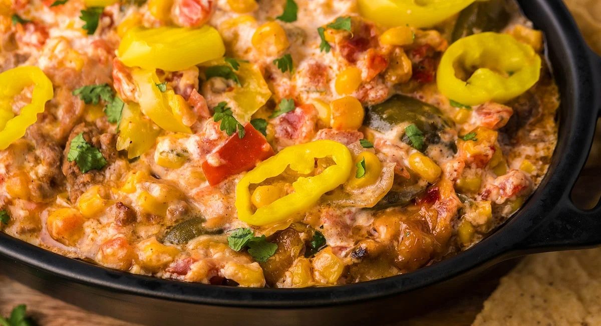 Overhead image of loaded slow cooker taco dip with garnish.