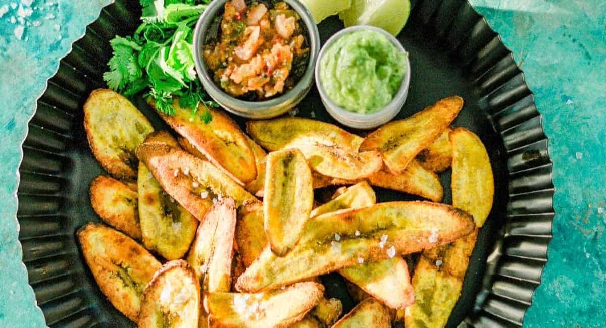 Overhead image of oven baked plantain chips with dips on the side.
