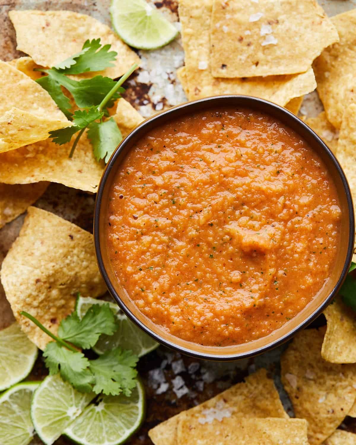 Mango habanero salsa in bowl with chips around.