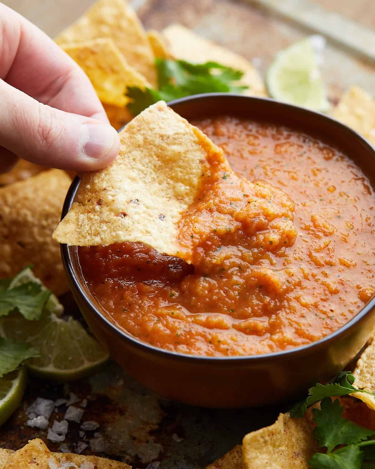 Chip being dipped in roasted mango habanero salsa.
