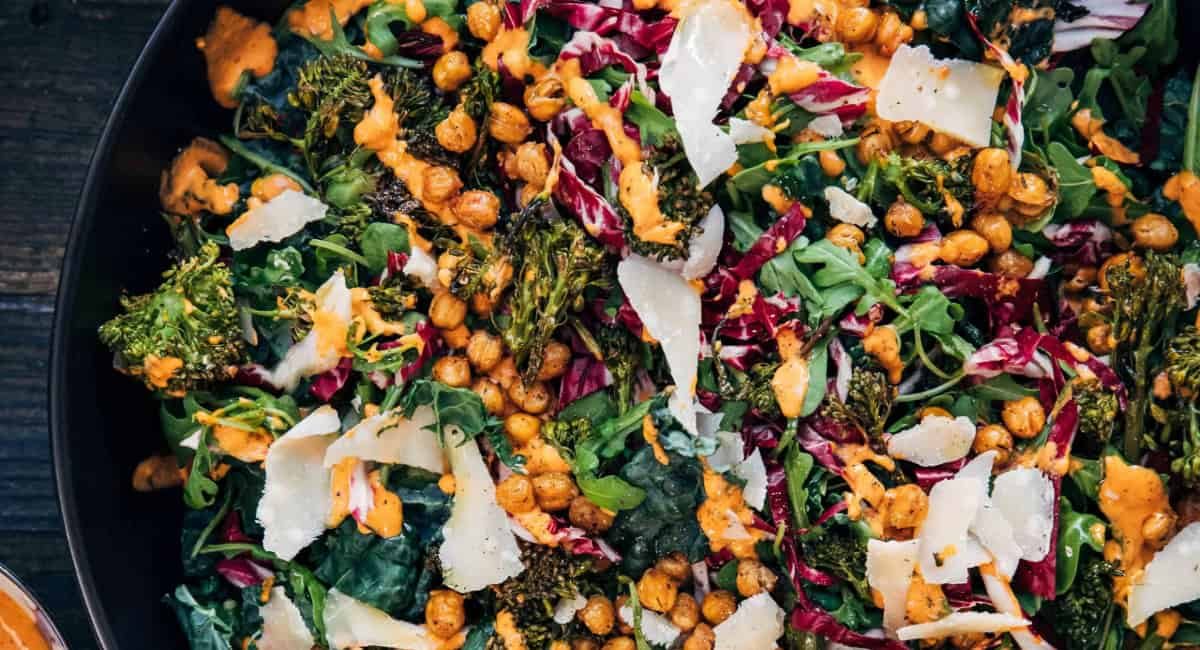 Overhead image of marry me chickpea salad with garnish in black bowl.