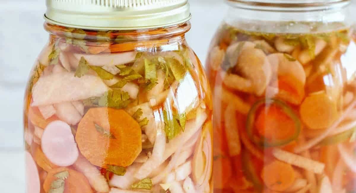 Up close image of Mexican pickled vegetales in glass jars.