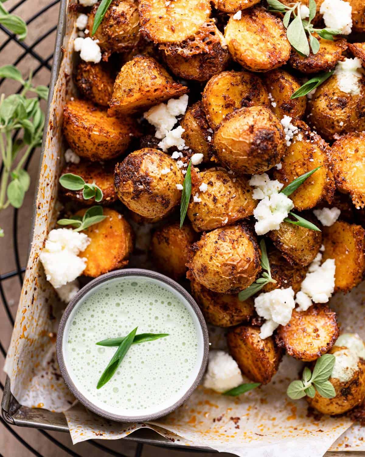 Overhead up close image of roasted Mexican potatoes with garnish and dip on the side.