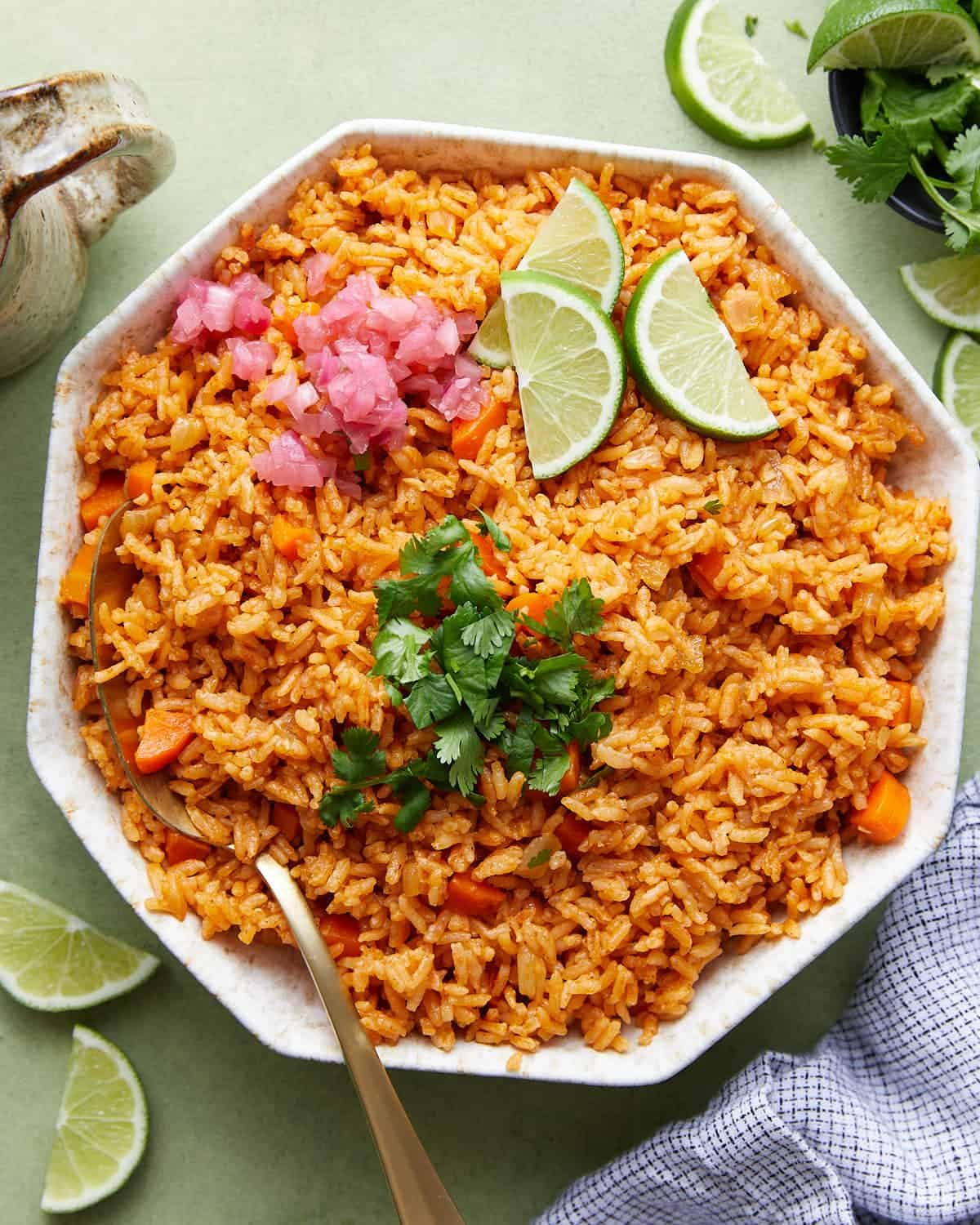 Overhead image of Mexican rice with garnish in white bowl with spoon.