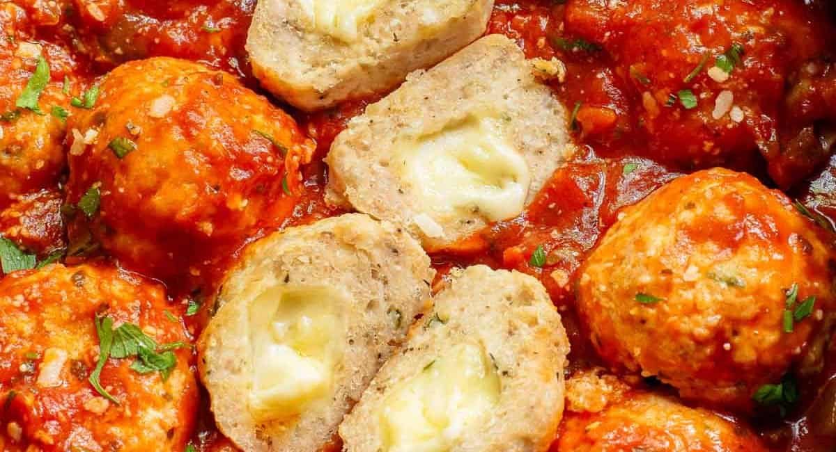 Overhead imge of mozzarella stuffed meatballs with garnish in red sauce.