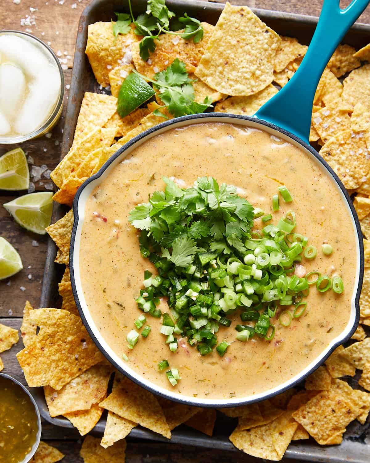 Overhead shot of mozzarella queso in a blue cast iron skillet with chips around.
