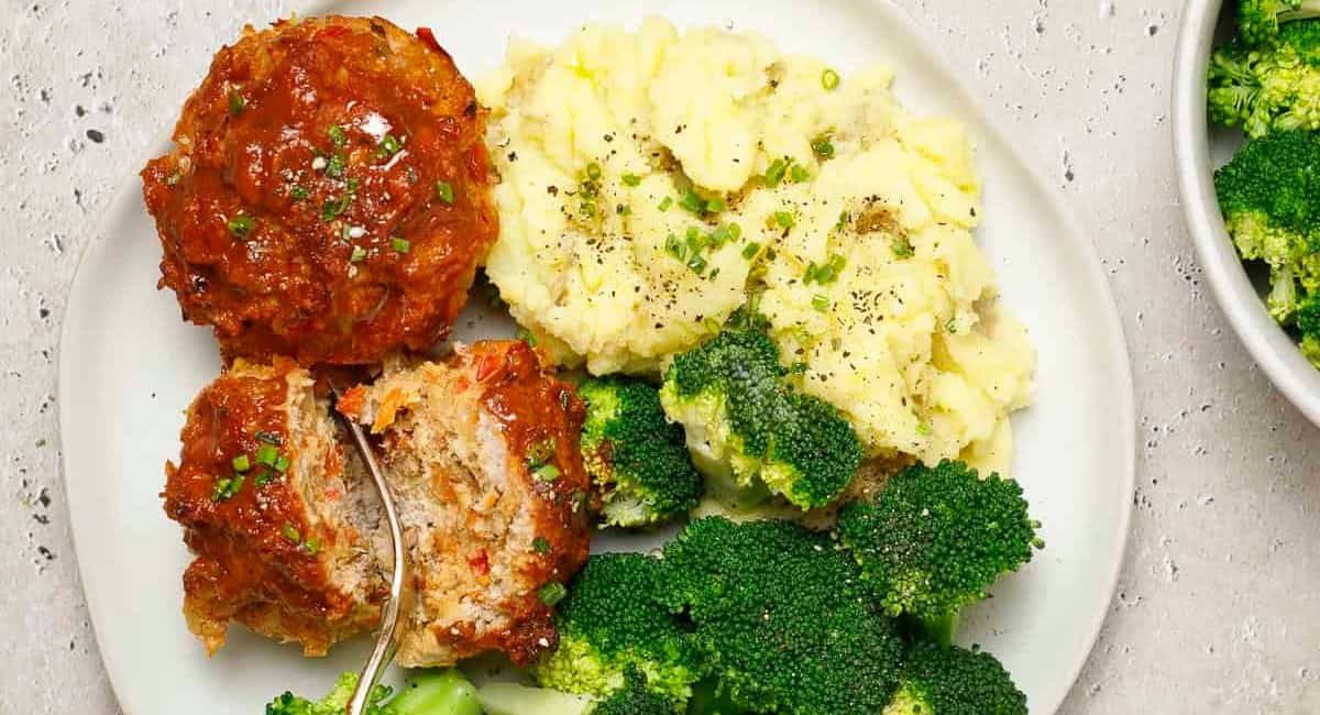 Overhead image of muffin pan turkey with mashed potatoes and broccoli on the side.