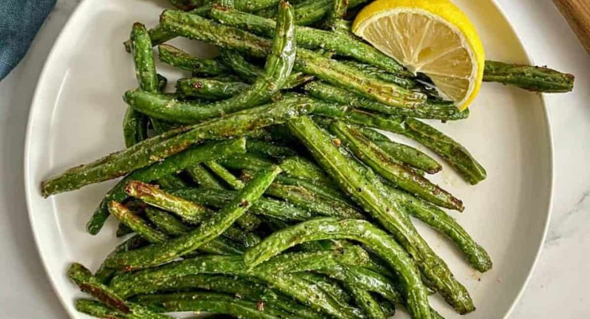 Overhead image of air fryer green beans on white dish.