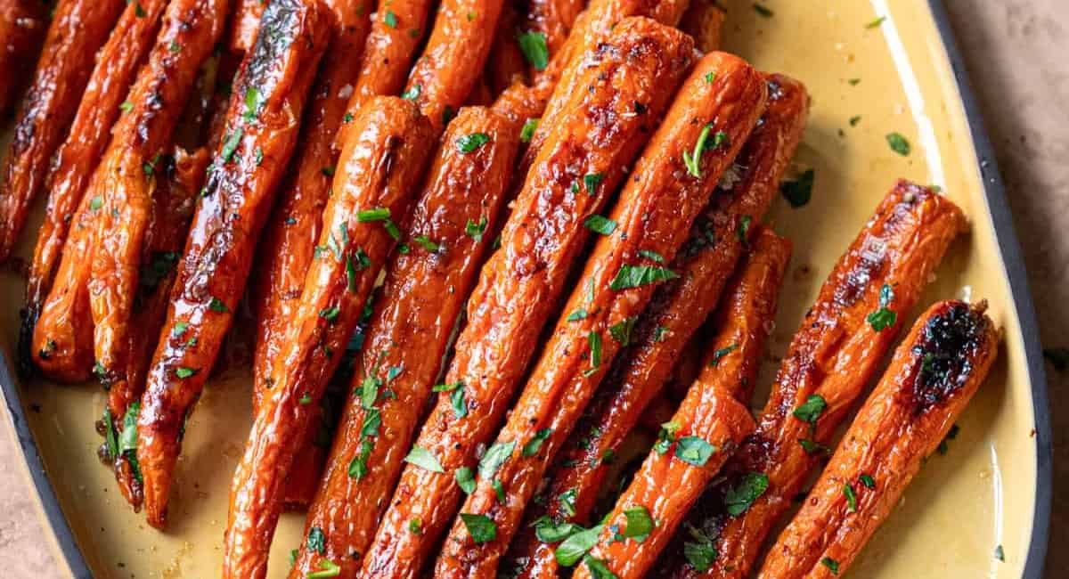 Overhead image of maple roasted carrots on yellow dish.