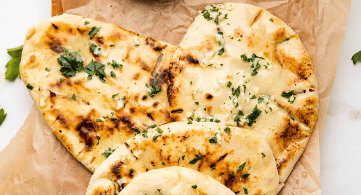 Overhead image of garlic cheese naan with garnish.
