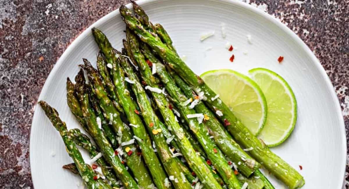 Overhead image of oven roasted asparagus with garnish on white dish.