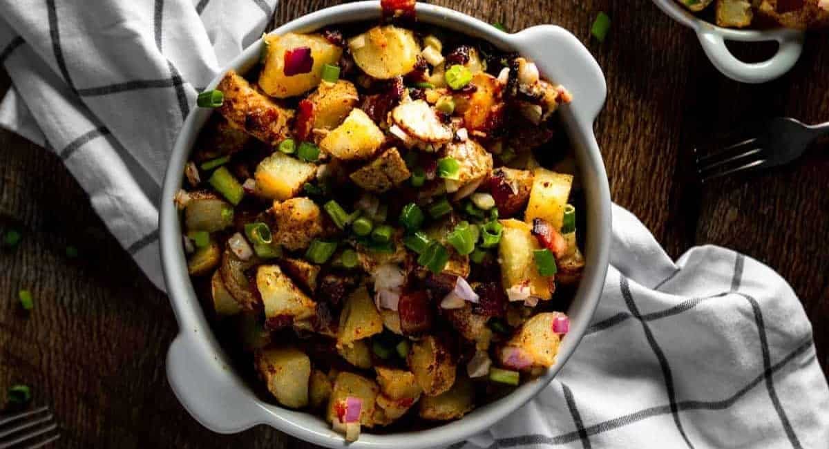 Overhead image of fried potato salad with bacon homemade aioli in white dish.