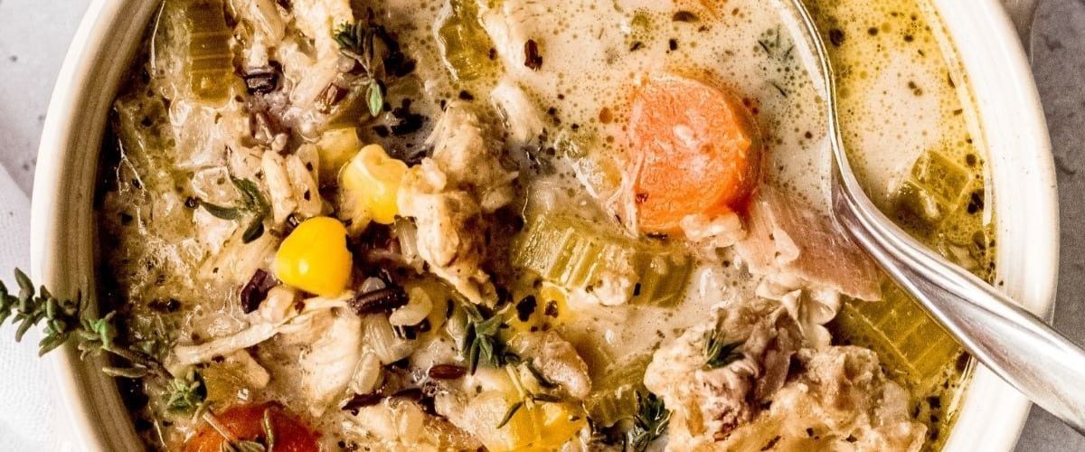 Instant pot chicken and rice soup in white bowl with garnish.