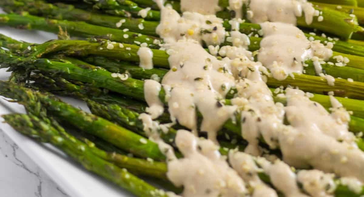 A photo of roasted asparagus with lemon tahini sauce.