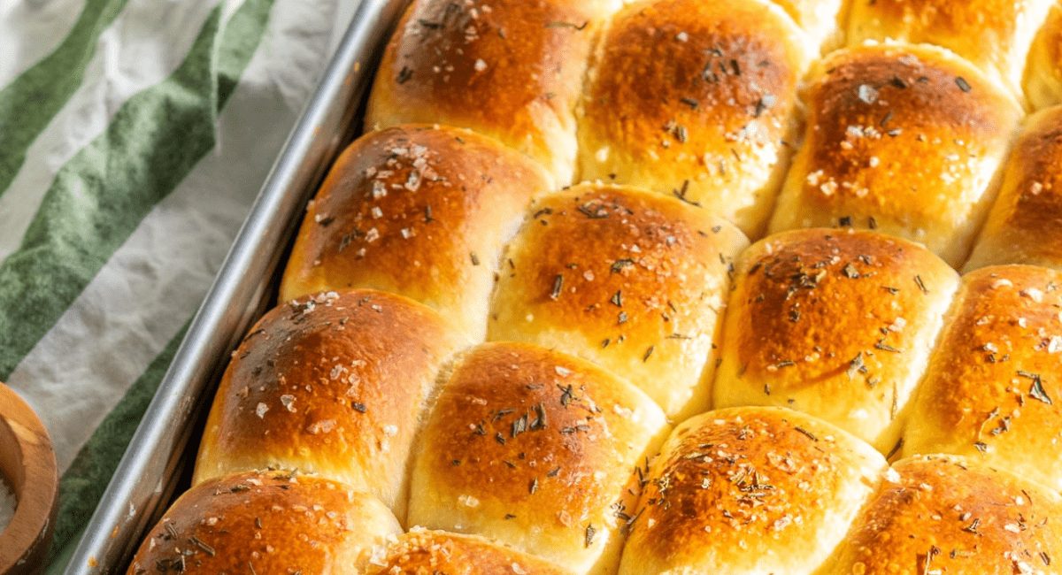 Overhead image of sourdough dinner rolls with rosemary and garnish.