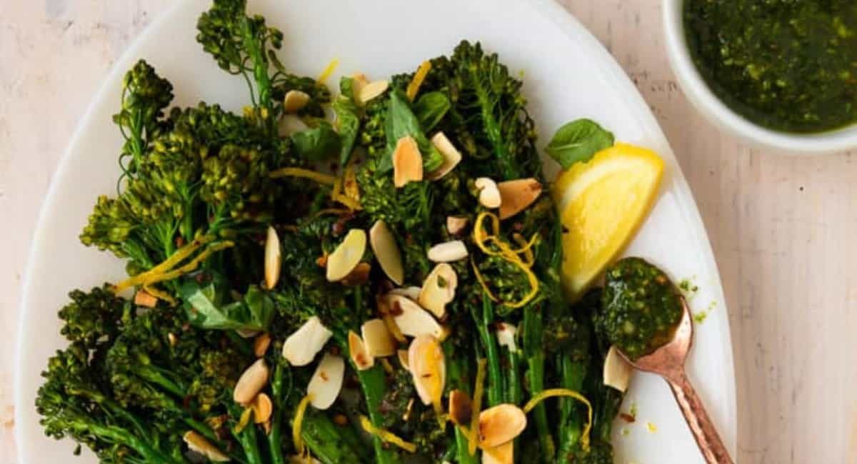 Overhead image of pesto broccolini with garnish on white dish.