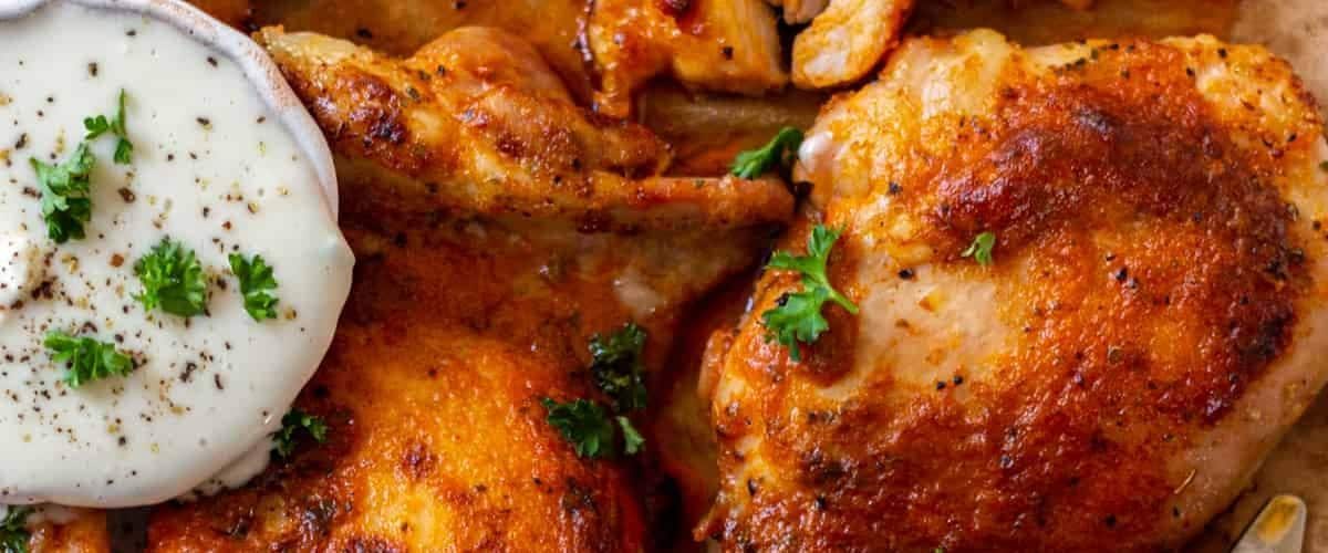 Baked buffalo chicken thighs with garnish.