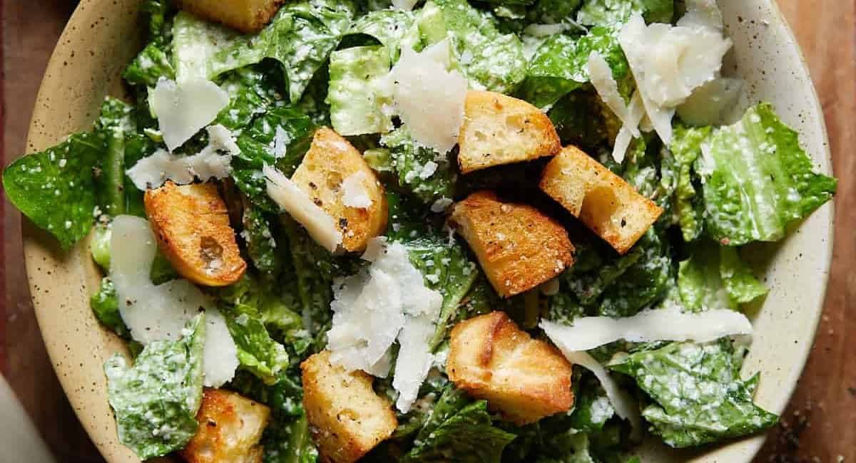 Overhead image of caesar salad in beige dish.