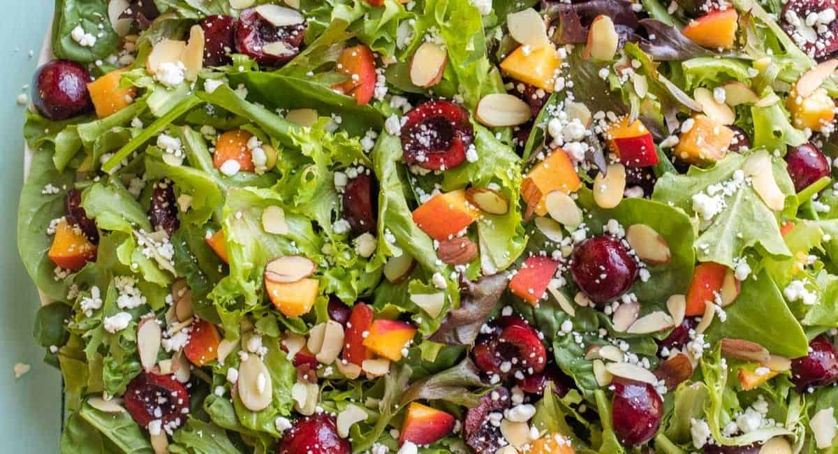 Overhead image of peach salad with cherries and goat cheese.