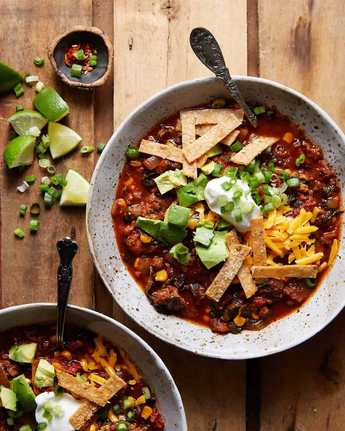 Overhead image of no bean turkey chili in two bowls with garnishes.