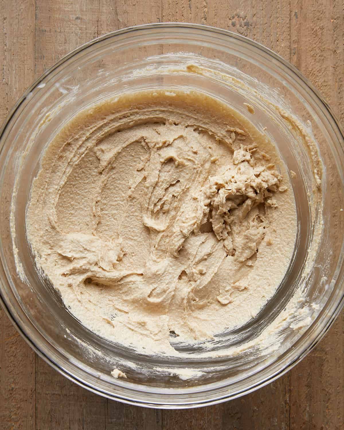 Overhead image of beating sugars for no chill chocolate chip cookies, showing brown and white sugar being mixed until smooth and glossy for a chewy cookie dough base.
