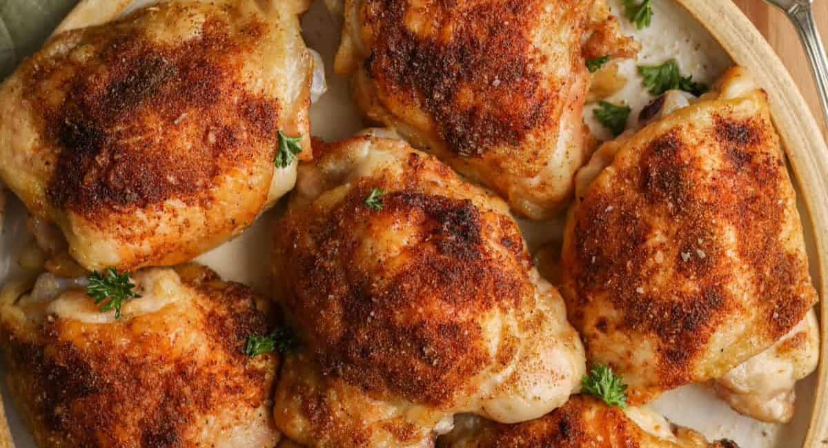 Overhead image of crispy oven-baked chicken thighs (bone-in) on dish with garnish.