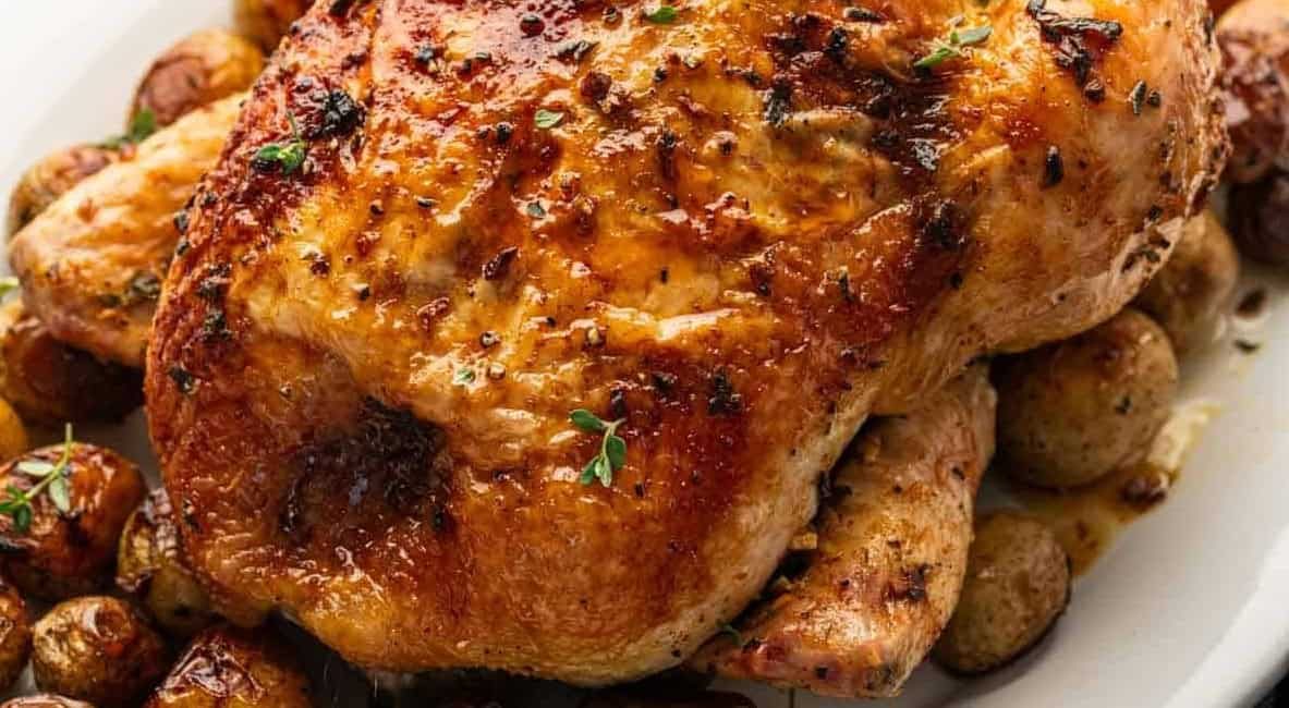 Up close image of oven roasted chicken and potatoes with garlic and herbs.