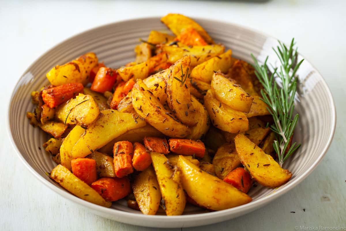 Overhead image of oven baked potatoes with Jamaican curry and caraway fruits.