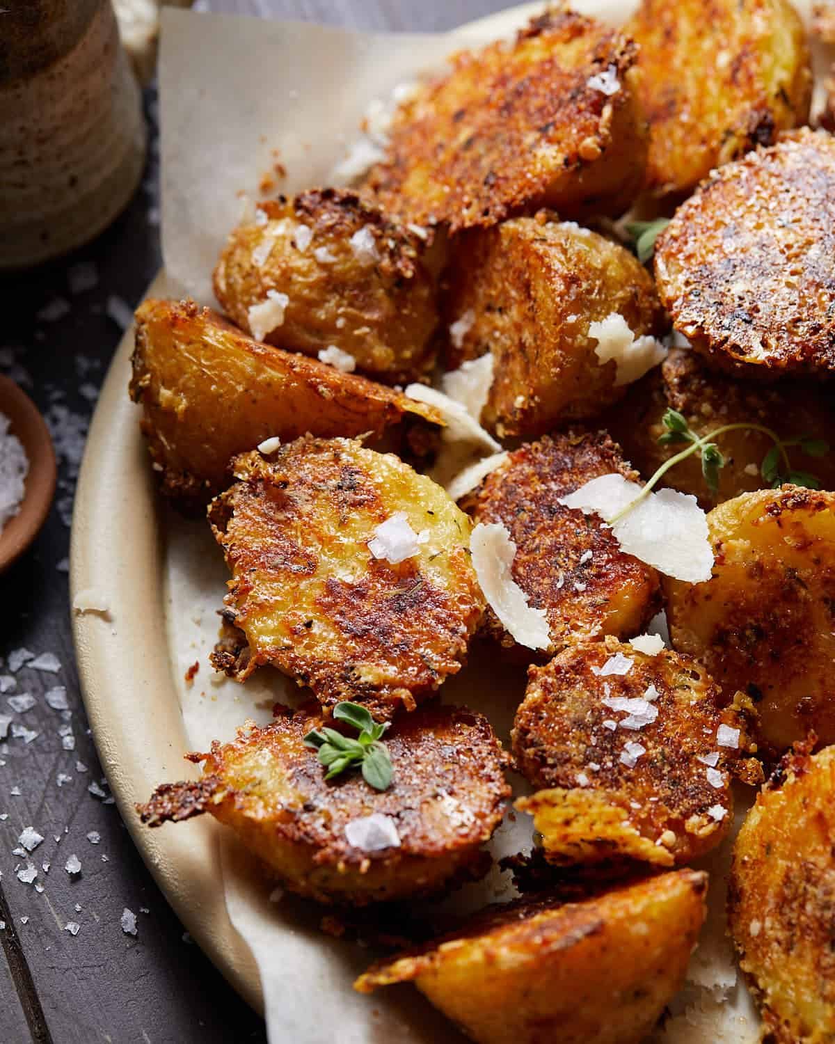 Crispy yukon gold potatoes on a plate with parmesan cheese on top.