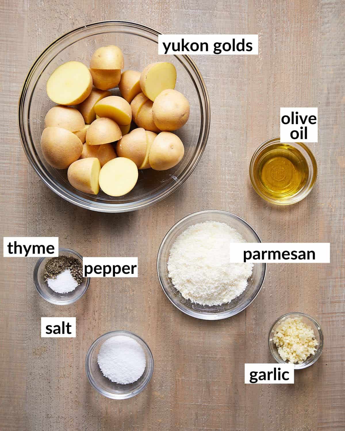 Ingredients needed to make yukon gold roast potatoes in glass bowls.