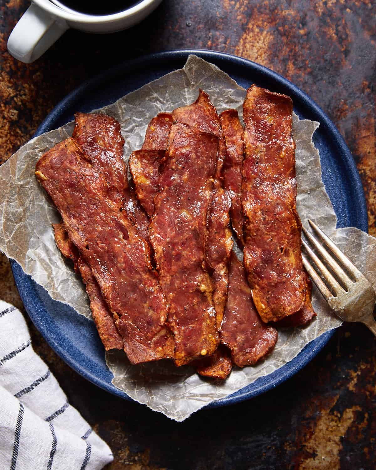 Oven baked turkey bacon on a blue plate.
