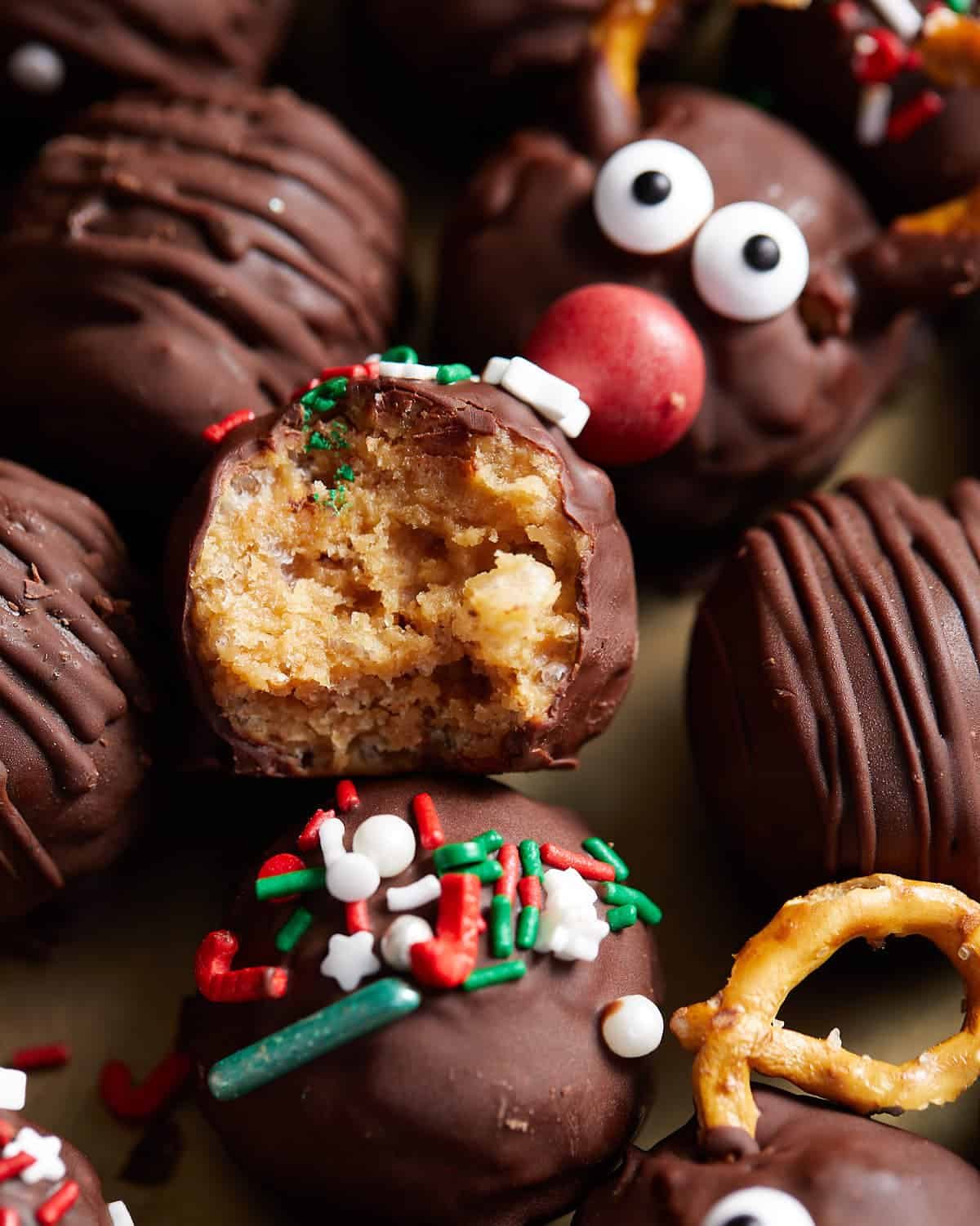 Up close image of peanut butter balls with rice krispies. Decorated with red, green, and white sprinkles and pretzel.