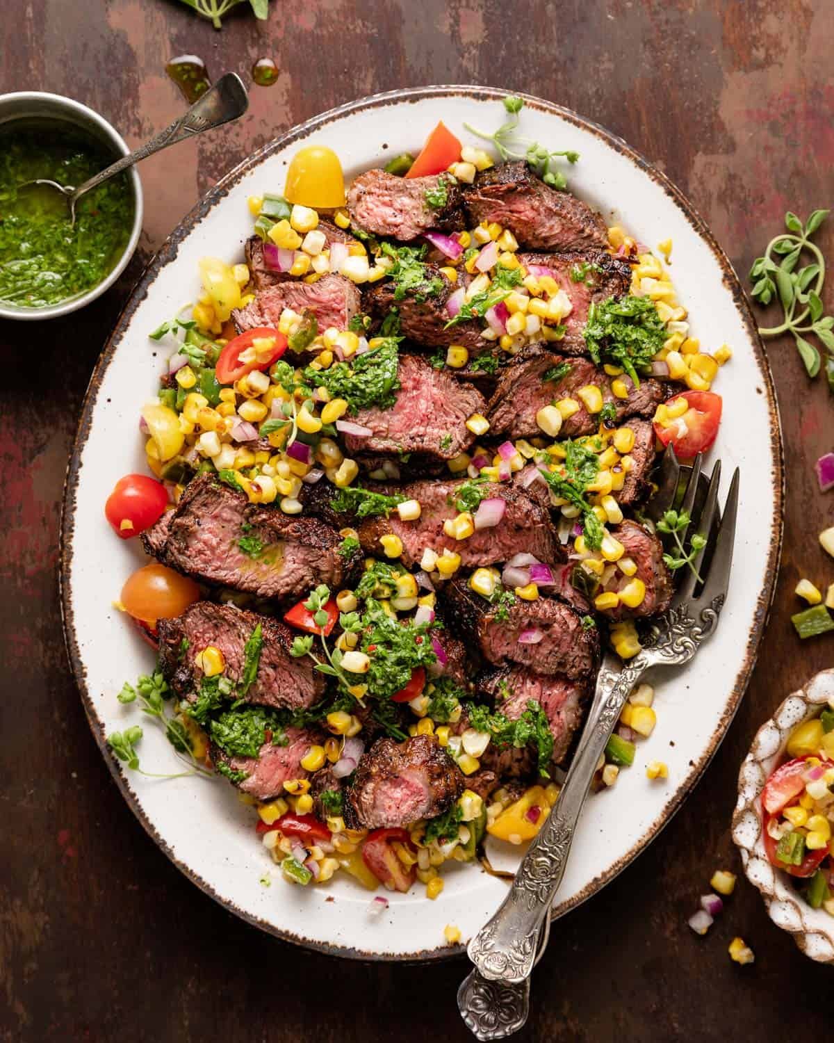Sliced picanha steak with chimichurri and corn salsa on top.