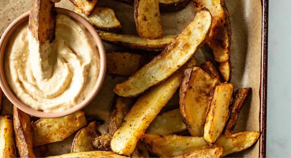 Overhead image of potato wedges with roasted garlic dip.