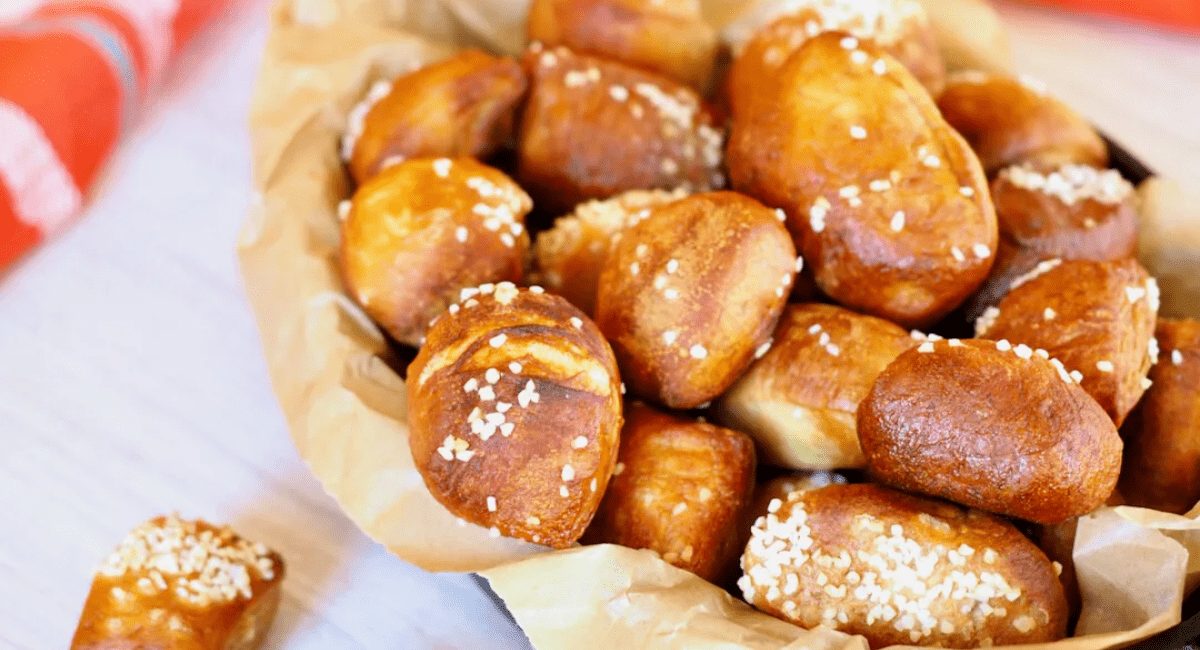 Pretzel bites topped with salt and served in a basket on a white table.