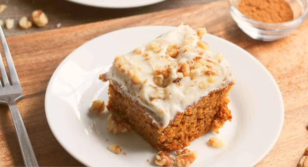 Overhead image of pumpkin cake with cream cheese frosting from scratch on white dish.