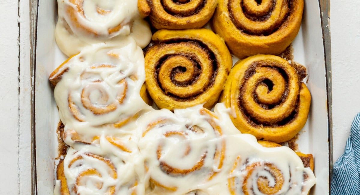 Overhead image of pumpkin cinnamon rolls with mape cream cheese frosting.