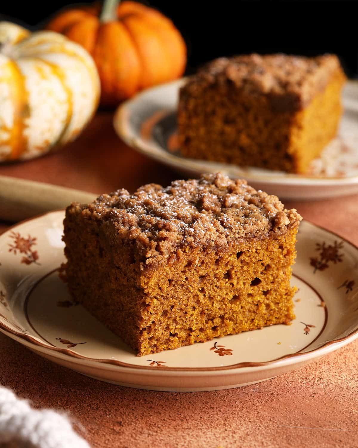 A slice of pumpkin coffee cake showing the moist pumpkin cake and thick brown sugar crumb topping.