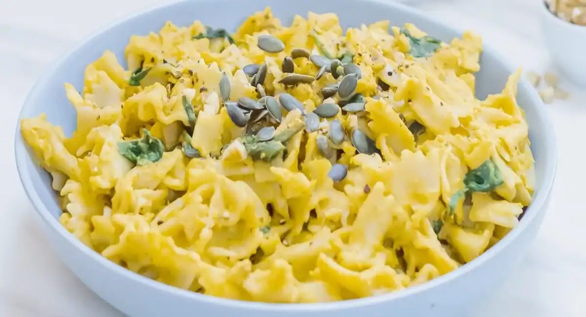Up close image of pumpkin pasta with spinach and walnuts.