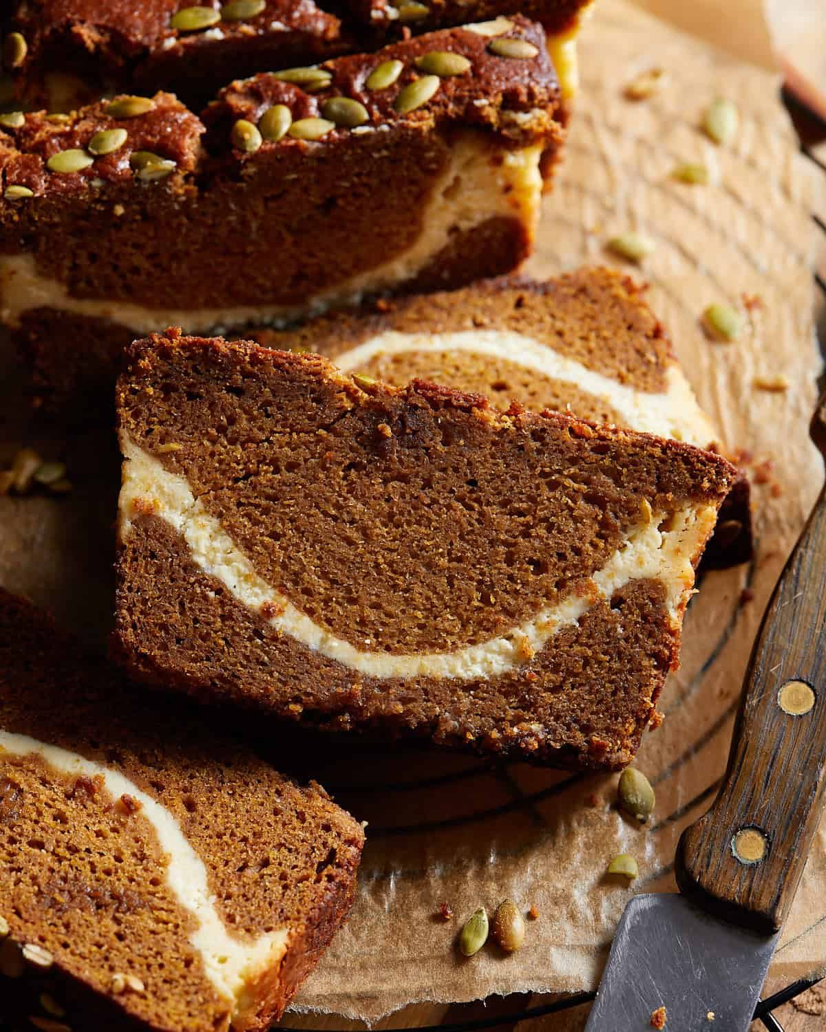 Pumpkin bread with cream cheese swirl on parchment paper sliced.