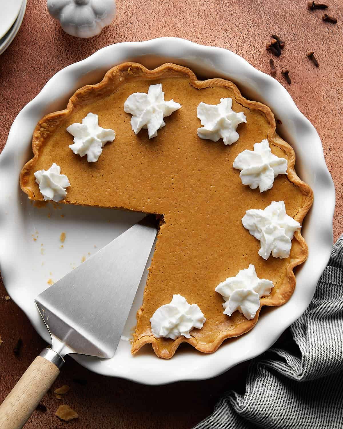 Overhead image of creamy pumpkin pie with cream cheese & condensed milk baked in a white pie dish, showcasing a smooth pumpkin filling and classic fall dessert presentation.