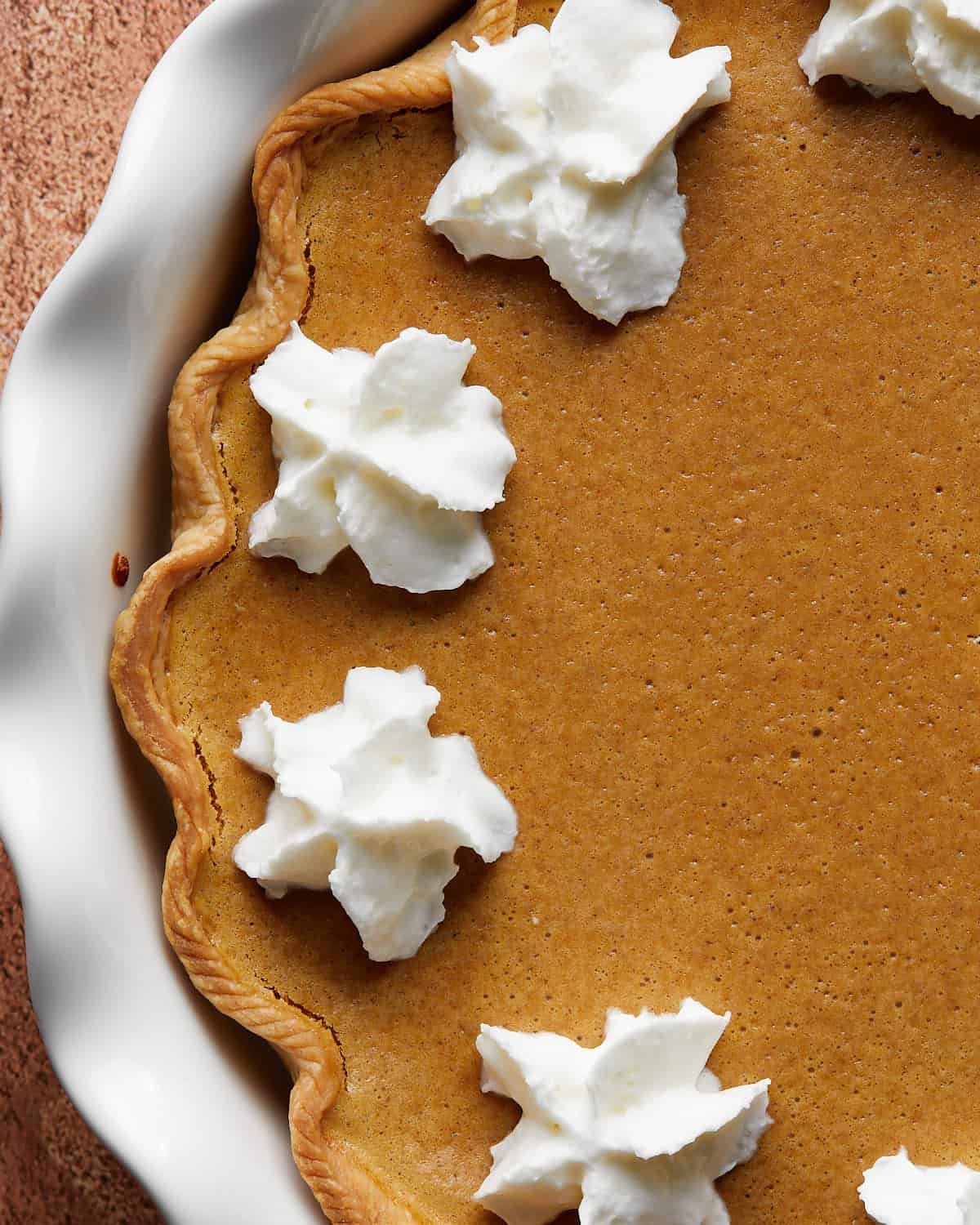 Up close image of a slice of pumpkin pie with cream cheese & condensed milk, showing the smooth, creamy filling and flaky crust.