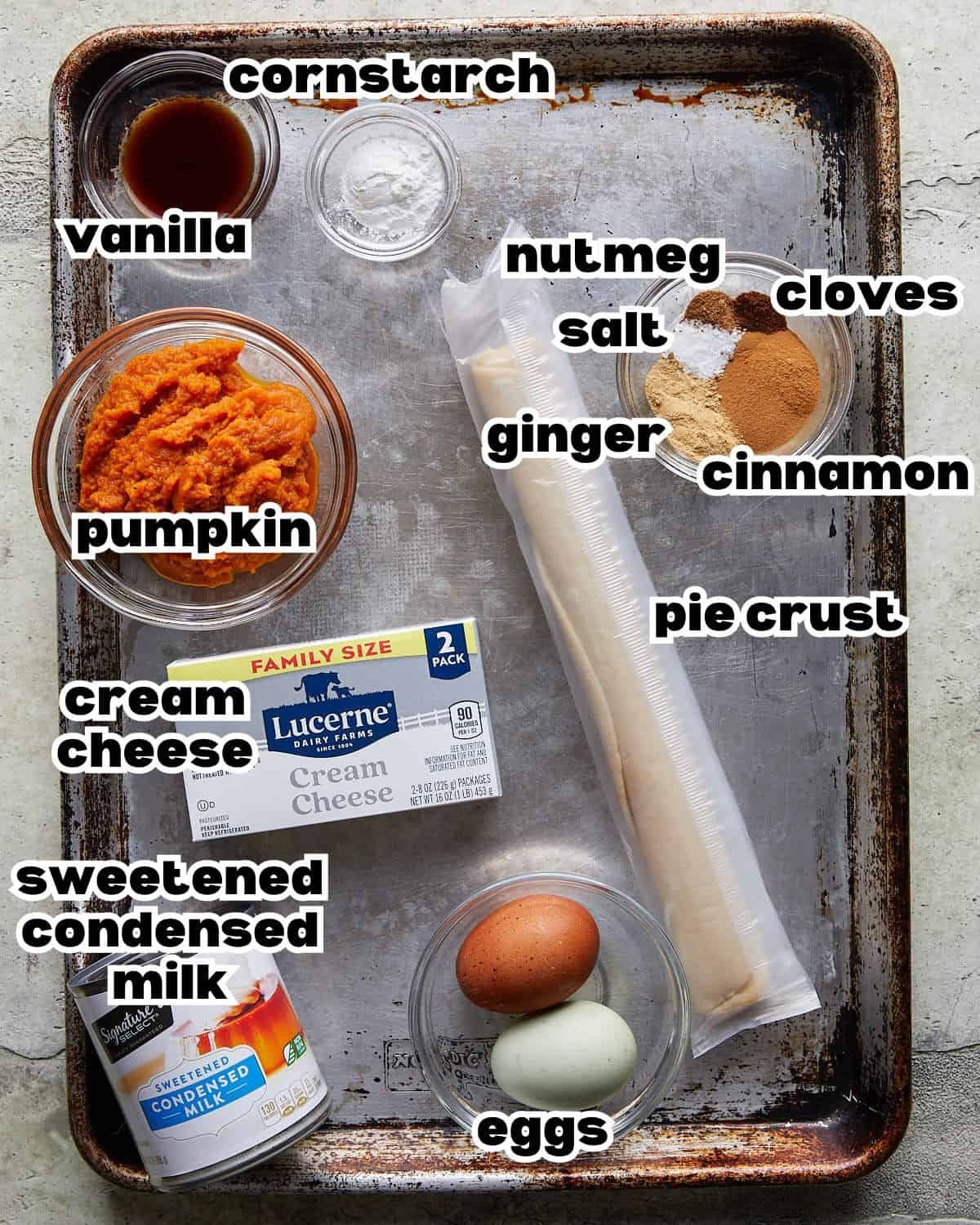 Overhead image of ingredients needed to make pumpkin pie with cream cheese & condensed milk, including pumpkin puree, cream cheese, sweetened condensed milk, eggs, spices, and pie crust.