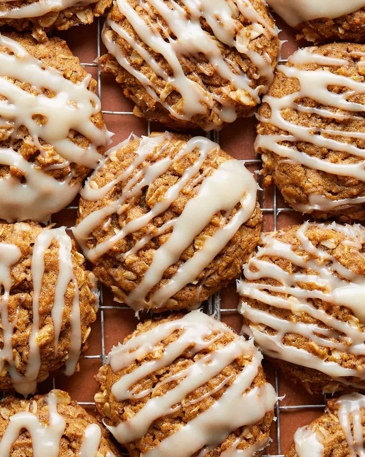 Up close image of soft and chewy pumpkin oatmeal cookies topped with a creamy cream cheese glaze, highlighting the texture and cozy fall flavors.