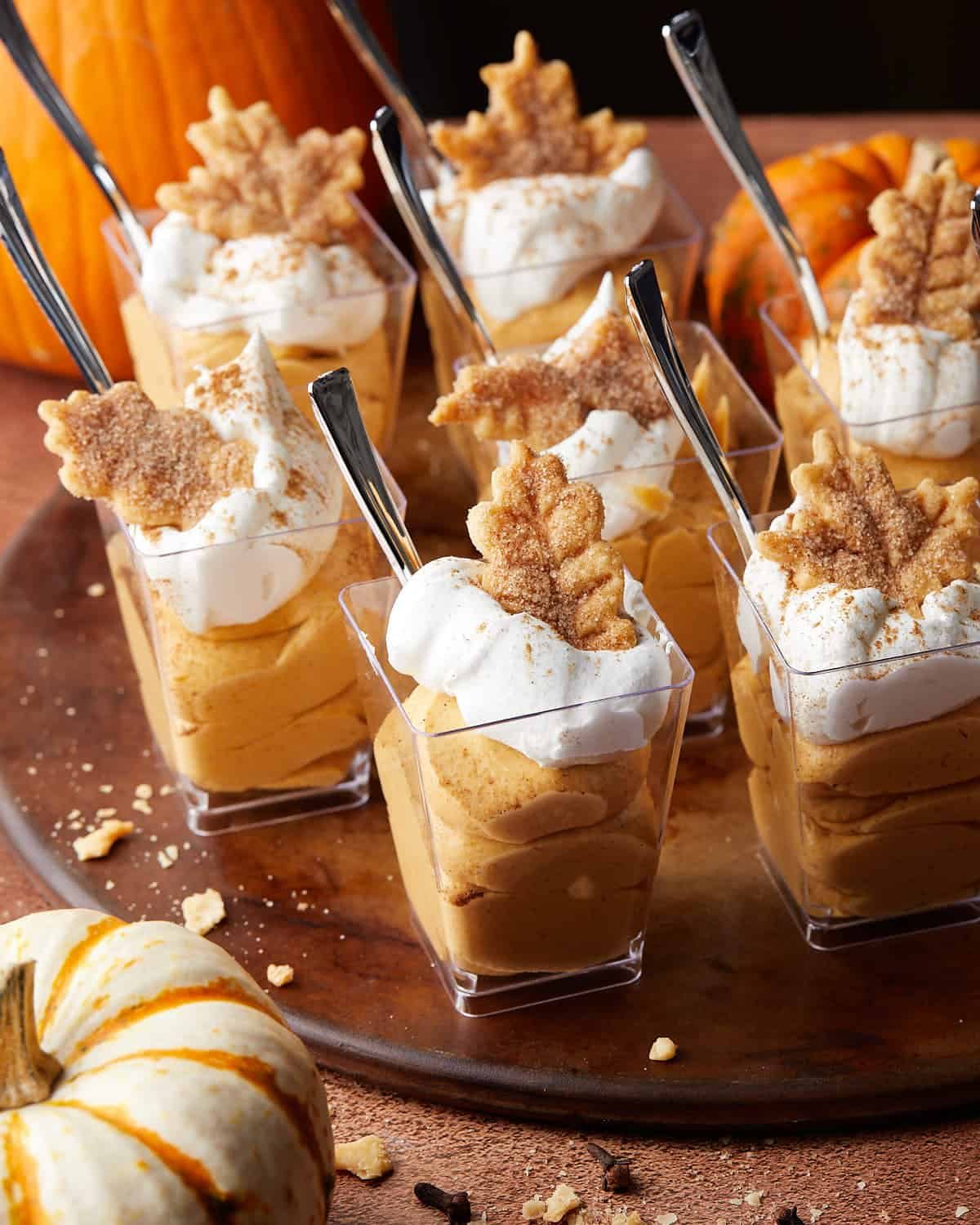 Overhead image of creamy pumpkin pie in a cup layered with whipped topping and warm fall spices, served in individual dessert cups.